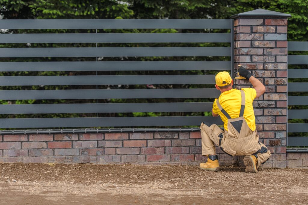 brick fence contractor finalizing the installation of a fence